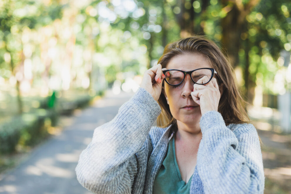 Woman rubbing her irritated eyes outside