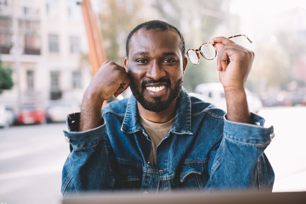 Happy guy holding glasses outside